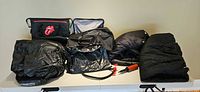 Group shot of all items: two sleeping bags, two folded air mattresses, Nike duffle, Rolling Stones cooler, hand pump