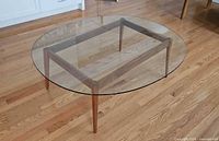 Full view of coffee table showing oval glass top on walnut base