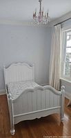 Full view of white twin bed frame with mattress