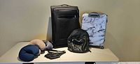 Group shot showing both suitcases, backpack, belt bag and two neck pillows