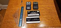 Lot overview showing two calculators, geometry set components and storage tin