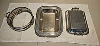 Three silver-plated serving pieces laid out: pie coaster, open tray, covered vegetable server