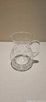 Full view of clear glass pitcher showing frosted circle pattern and handle