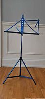 Full view of metallic blue folding tripod music stand set at mid height