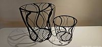 Both black metal wire baskets side by side