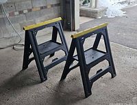 Full view of both black Stanley sawhorses standing on floor