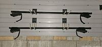 Two Thule steel crossbars with foot packs hung on wall