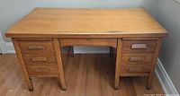 Front view of oak pedestal desk with six drawers and center kneehole