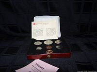 Set in open red case showing coins and information card