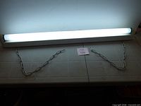 Fixture illuminated showing tube lit and hanging chains