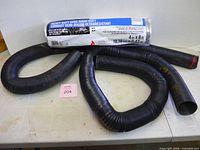 All three items: packaged semi-rigid duct and two black expansion hoses
