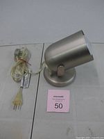 Side view of brushed nickel spotlight with cord and plug visible