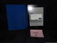 Kindle with screen on inside blue cover, cable visible