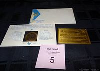Group shot of medallion in card, envelope, and brass life member card