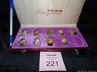 Open Peking Jewelry box with nine enamel mask pendants, empty tenth slot visible