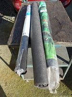 Three landscape fabric rolls side by side on bench