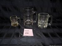Three clear glass A&W mugs of different sizes on black background