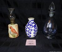 Front view of all three items: oil lamp, vase, decanter