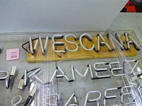 Block letter "WESCANA" sign on wood and portion of larger sign beneath