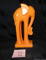 Front angled view of orange ceramic elephant figurine on base