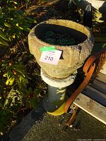 Top view of one concrete urn on pedestal with moss and lot tag visible