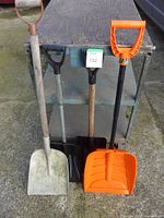 Front view of all four shovels leaning against cart