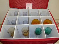 Open storage case showing 12 divider slots with colored cordial glasses inside