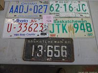 Five licence plates from ON, BC, AB, SK (2) laid out on table