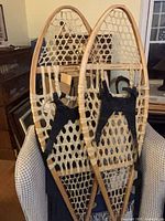 Full view of both wooden snowshoes leaning on chair