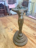 Front view of bronze-colored nude figurine on stepped base