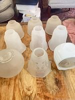 Eight of the nine vintage white glass shades displayed on table