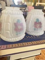 Two frosted glass floral shades on books showing ribbed design and painted panels