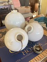 Three white glass lightning rod balls grouped together showing size difference and openings