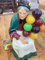 Front view of figurine showing woman with balloons and basket