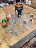 group of glass shakers, spare tops, tomato ceramics on table