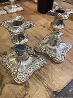 Pair of ornate silver-plated candlesticks, angled view
