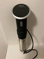 Full view of Anova Precision Cooker standing upright showing black control head, stainless steel body, attached cord