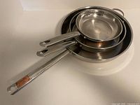 Three nested copper-clad stainless skillets