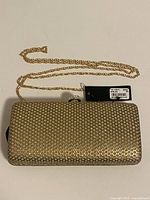 Front view of gold Guess by Marciano clutch with chain strap displayed