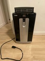 Front view of Haier black and silver portable air conditioner with power cord visible