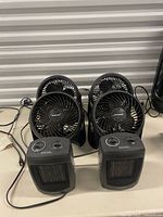 Four Honeywell TurboForce fans behind two ceramic heaters on table