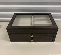 Closed jewelry box showing glass lid and two front drawers