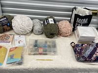 Overview of yarn skeins, craft kits, organizer box, tote, canvases and pouch