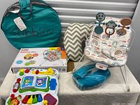 Lot overview showing play tent bag, boxed bouncer, assembled bouncer, cushion, and musical toy