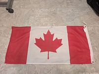 Full view of Canadian flag laid flat showing design, size, grommets, header