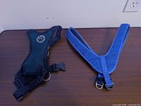 Green/black mesh harness and blue V-strap harness on tabletop