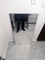 Front view of rectangular frameless mirror placed against wall