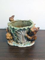 Front view of ceramic planter showing two rabbits and tree-stump texture