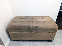 Front side view of ottoman showing upholstery color, tufting and overall wear