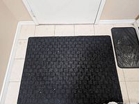 Checker-texture black door mat and rubber tray at entryway
